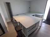 an image of a kitchen with a white counter and a black trash can