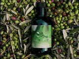 une bouteille d'huile d'olive posée sur une pile d'olives