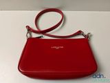 a red purse with a strap on it sitting on a table