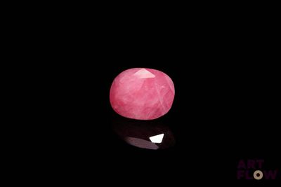 un gros plan d'une pierre rose sur une surface noire