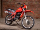 a red dirt bike parked in front of a brick wall