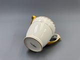 a white coffee cup with a gold handle on a table