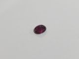 an oval shaped red garnet stone on a white surface