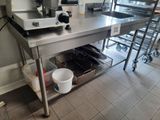 a large stainless steel work table with a cup on it