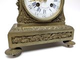 a gold clock with roman numerals on the face