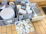 beaucoup d'assiettes et de tasses dans un bac posé par terre