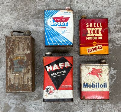 Plusieurs vieux bidons d'huile sont alignés sur une surface en béton