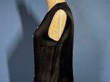 a black vest on a mannequin stand against a blue wall