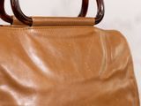 brown leather handbag with wooden handles on a white background