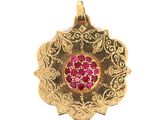 une photo en gros plan d'un pendentif en or orné d'une pierre rose