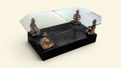 une table en verre sur laquelle sont posées des statues et un miroir sur le dessus
