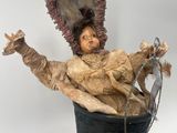 a statue of a woman sitting in a bucket on a table