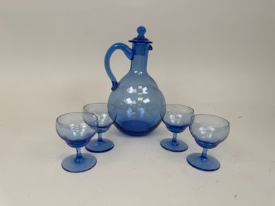 a blue glass pitcher and four glasses on a table