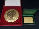 l'image d'une médaille d'or dans un coffret rouge posé sur un fond noir