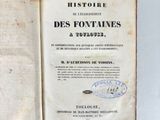 someone is holding an old book open on a white surface