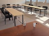 des tables et des chaises dans une pièce vide, avec un ordinateur portable posé sur la table
