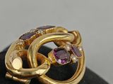 a close up of a gold ring with purple stones on a black surface
