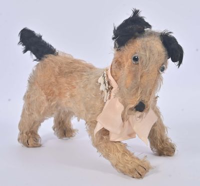 un petit chien brun avec un nœud rose autour du cou