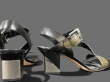 a pair of black and silver sandals on a gray surface