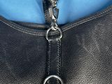 black leather handbag with a silver metal clasp on a blue background
