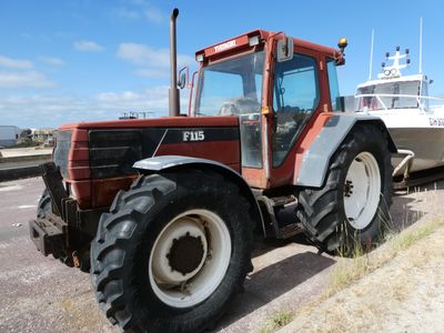 a tractor parked next to a boat on the side of the road