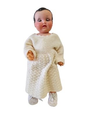 baby doll dressed in a white knitted dress and white shoes