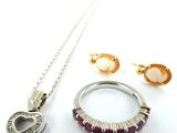 un collier, des boucles d'oreilles et une bague posés sur une surface blanche