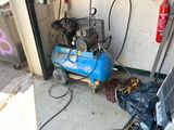 un compresseur d'air bleu posé dans un garage à côté d'un ordinateur portable