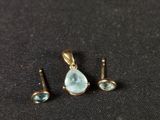 a close up of a pair of earrings and a pendant on a black surface