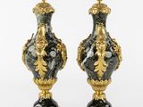 two black and gold vases sitting on top of a white surface