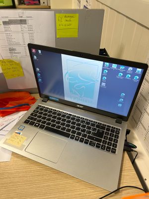un ordinateur portable posé sur un bureau, à côté d'une pile de papiers