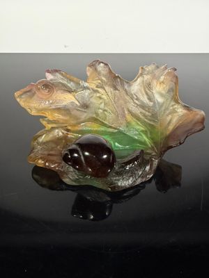 a glass figurine of a leaf and acorn on a black surface