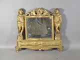 a small gold clock with a mirror on top of it