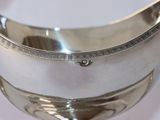 a silver bowl with a handle on a white table