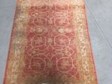 an image of a red and beige rug with a tag on it
