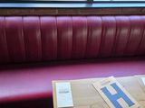 a red booth with a red leather bench and a window