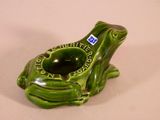 a green frog shaped ashtray sitting on a table