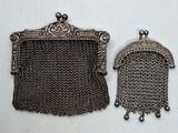deux porte-monnaie en métal argenté et un porte-monnaie en cotte de mailles posés sur une surface blanche