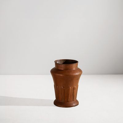 un petit vase brun posé sur une surface blanche