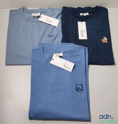 trois t-shirts posés sur une table, avec une étiquette de prix
