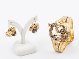 two pairs of gold rings and earrings on a white stand