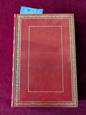 un livre rouge posé sur une table recouverte d'un tissu violet