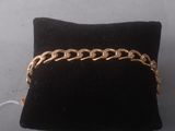 a close up of a gold chain bracelet on a black pillow