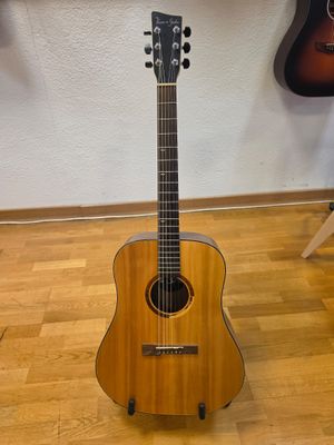 an acoustic guitar sitting on top of a wooden floor next to a wall