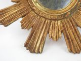 a gold starburst shaped mirror on a white surface
