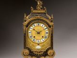a gold clock with roman numerals on the face