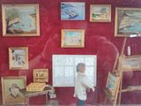 a man that is standing in front of a display of paintings