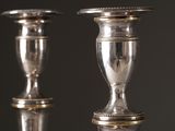 pair of antique silver candlesticks on a mirrored surface