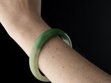 a woman ' s arm with a green bracelet on it