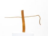 sculpture of a wooden cross on a white pedestal with a white background